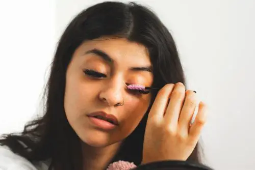 woman applying coconut oil on eyelashes