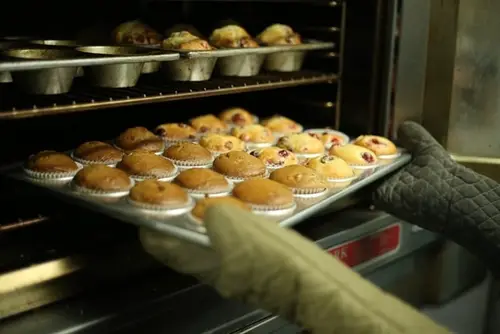 Person taking a tray of muffins from the oven