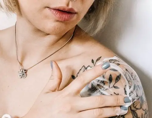 Woman Applying coconut oil on tattooed skin