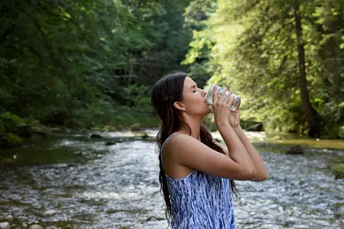 Girl in the nature surrounding drinking water